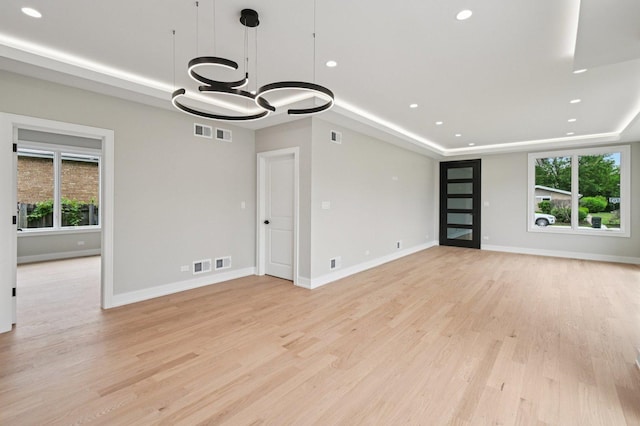 2700 Fontana Dr, Glenview, IL 60025 - unfurnished living room featuring a tray ceiling, a chandelier, light wood finished floors, and recessed lighting