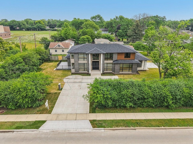 2700 Fontana Dr, Glenview, IL 60025 - modern home featuring a front lawn, a shingled roof, view of scattered trees, and concrete driveway