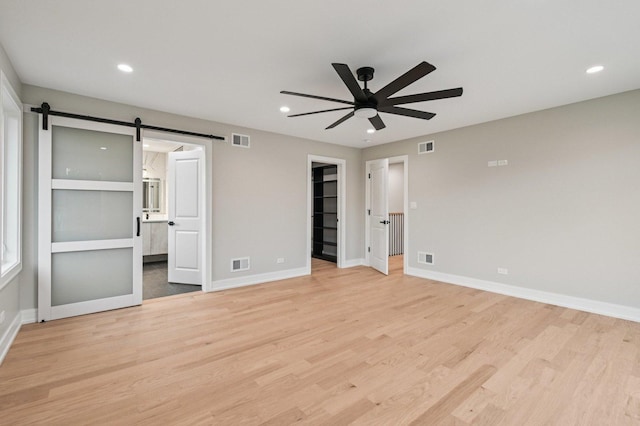 2700 Fontana Dr, Glenview, IL 60025 - unfurnished bedroom featuring a barn door, light wood-style floors, a walk in closet, recessed lighting, and ensuite bathroom