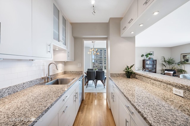 1325 N State Pkwy Unit 7A, Chicago, IL 60610 - kitchen featuring light wood-style flooring, decorative backsplash, glass insert cabinets, and light stone counters