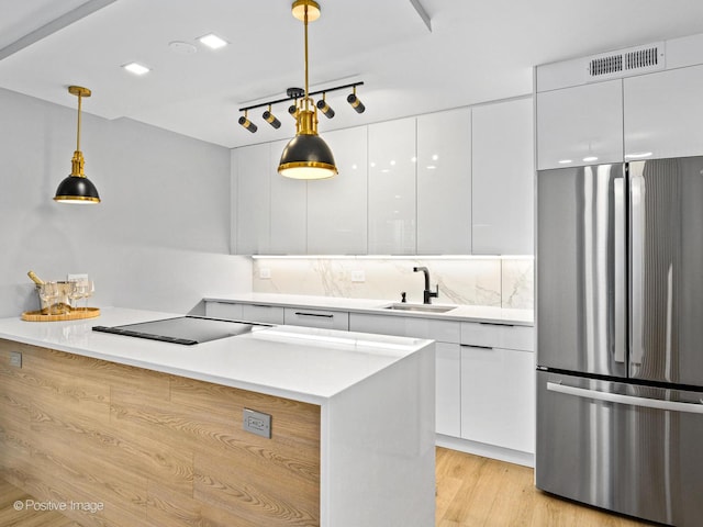 1455 N Sandburg Ter Unit 209B, Chicago, IL 60610 - kitchen with freestanding refrigerator, modern cabinets, black electric cooktop, white cabinetry, and hanging light fixtures