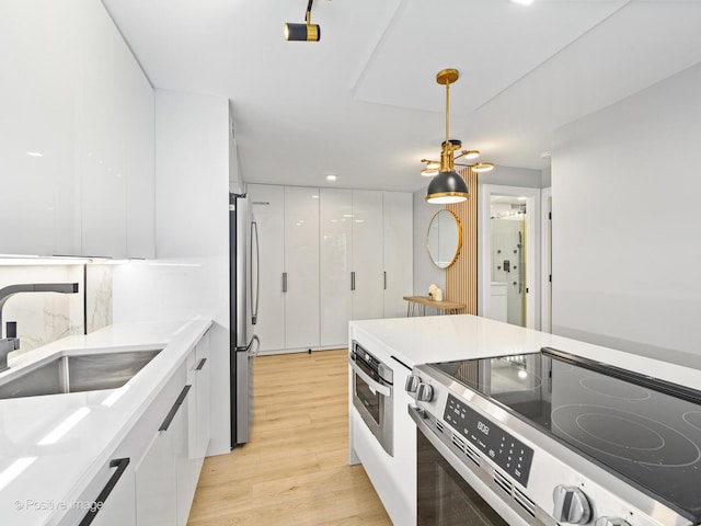 1455 N Sandburg Ter Unit 209B, Chicago, IL 60610 - kitchen featuring stainless steel appliances, modern cabinets, white cabinetry, light wood-type flooring, and light countertops
