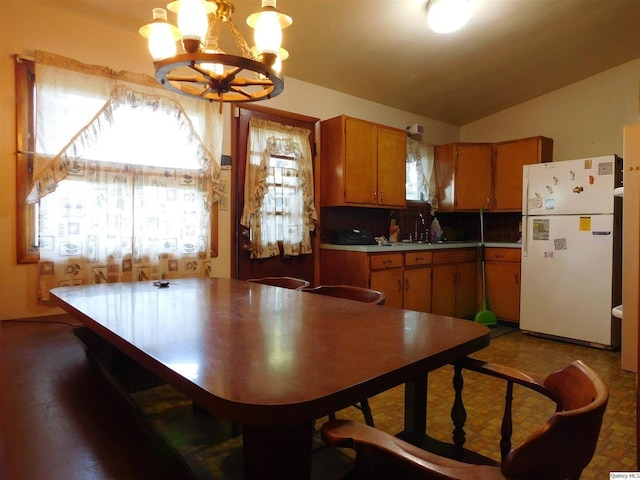 3411 Payson Rd, Quincy, IL 62305 - kitchen featuring freestanding refrigerator, a chandelier, brown cabinets, lofted ceiling, and backsplash