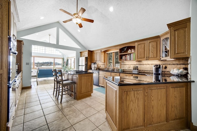328 Windermere Dr, Chesterton, IN 46304 - kitchen featuring stainless steel dishwasher, ceiling fan, backsplash, dark countertops, and brown cabinetry