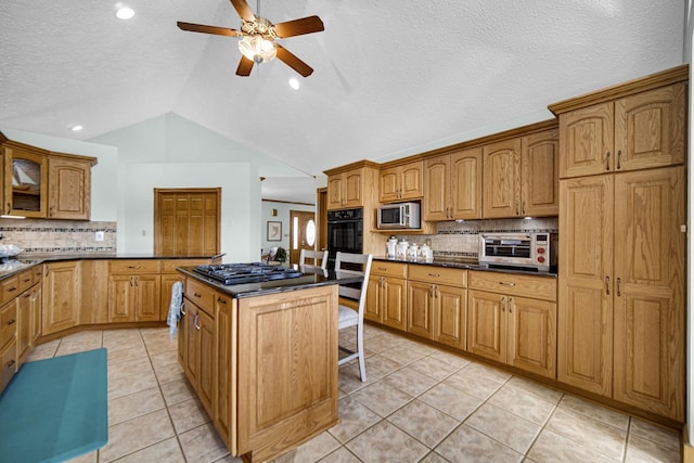 328 Windermere Dr, Chesterton, IN 46304 - kitchen featuring stainless steel microwave, a ceiling fan, vaulted ceiling, decorative backsplash, and dark countertops
