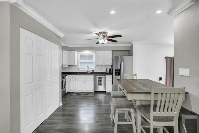 1901 Sumac Dr, Champaign, IL 61821 - kitchen featuring appliances with stainless steel finishes, dark countertops, crown molding, backsplash, and a ceiling fan