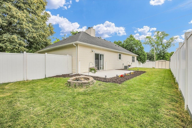 1901 Sumac Dr, Champaign, IL 61821 - rear view of house with a fire pit, a patio, a fenced backyard, a chimney, and a shingled roof
