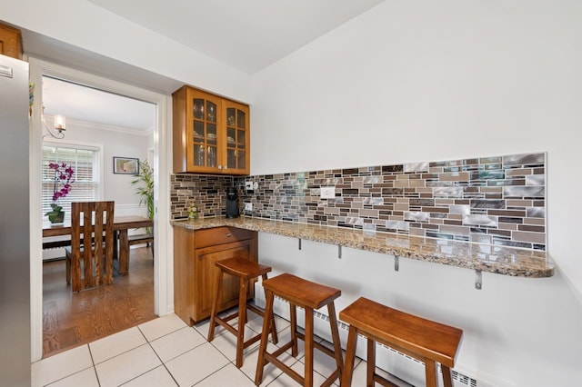 806 S Walnut Ave, Arlington Heights, IL 60005 - kitchen with brown cabinets, ornamental molding, glass insert cabinets, decorative backsplash, and a breakfast bar area