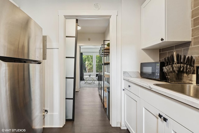 1709 W Wallen Ave Unit 1J, Chicago, IL 60626 - kitchen featuring freestanding refrigerator, black microwave, backsplash, white cabinetry, and dark wood-style floors
