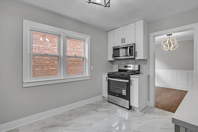 9007 S Cregier Ave, Chicago, IL 60617 - kitchen featuring appliances with stainless steel finishes, white cabinets, a chandelier, light marble finish flooring, and light stone counters