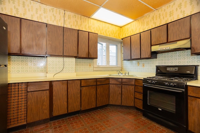 5028 N Sawyer Ave, Chicago, IL 60625 - kitchen featuring black range with gas cooktop, under cabinet range hood, wallpapered walls, dark floors, and light countertops
