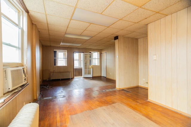 5028 N Sawyer Ave, Chicago, IL 60625 - empty room featuring radiator, wood finished floors, wood walls, cooling unit, and a paneled ceiling