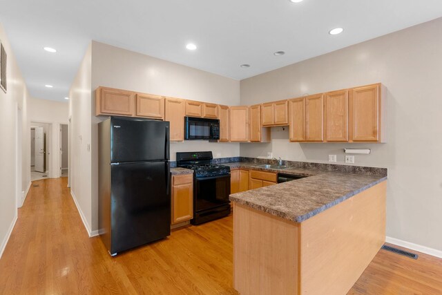 5028 W Lawrence Ave, Chicago, IL 60630 - kitchen with black appliances, dark countertops, light brown cabinets, light wood-style floors, and a peninsula