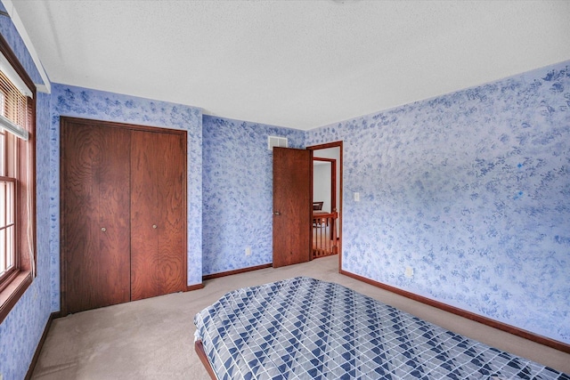 2904 Robeson Park Dr, Champaign, IL 61822 - carpeted bedroom with wallpapered walls, a textured ceiling, and a closet