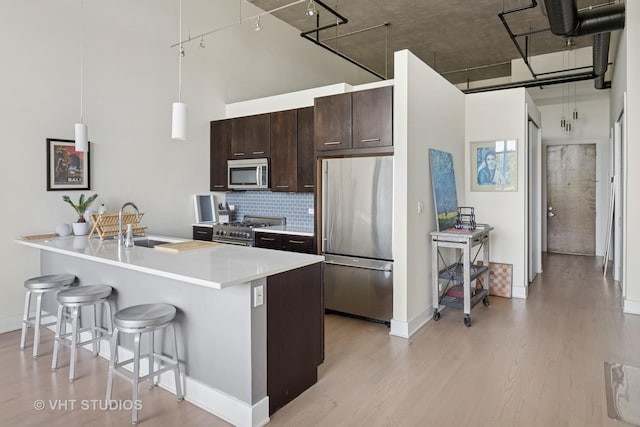 1800 W Grace St Unit 523, Chicago, IL 60613 - kitchen with high end appliances, light wood-type flooring, a breakfast bar area, dark brown cabinetry, and tasteful backsplash