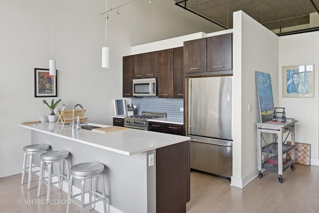 1800 W Grace St Unit 523, Chicago, IL 60613 - kitchen with high quality appliances, a breakfast bar area, light wood-type flooring, dark brown cabinets, and backsplash