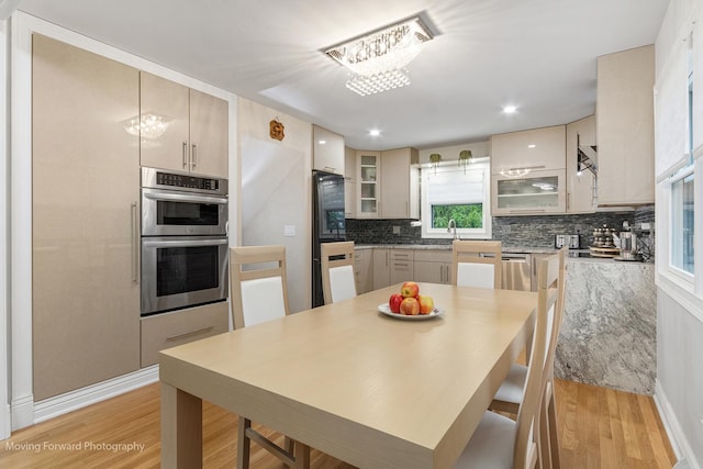 1145 S Chestnut Ave, Arlington Heights, IL 60005 - kitchen featuring stainless steel double oven, light wood-style flooring, tasteful backsplash, and glass insert cabinets