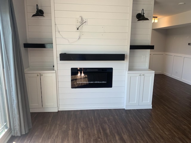 488 Fairview Dr Unit 0, Manhattan, IL 60442 - unfurnished living room featuring dark wood finished floors, a wainscoted wall, a decorative wall, and a glass covered fireplace