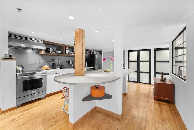 531 S Plymouth Ct Unit 602, Chicago, IL 60605 - kitchen featuring appliances with stainless steel finishes, exhaust hood, light countertops, white cabinetry, and light wood-style floors