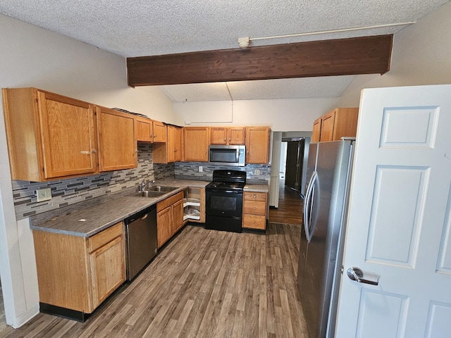 2875 N Vine St, Decatur, IL 62526 - kitchen with appliances with stainless steel finishes, wood finished floors, backsplash, brown cabinetry, and a textured ceiling