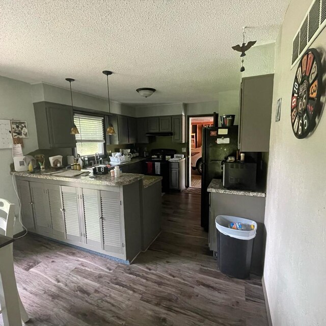 112 Crestview Dr, Hamilton, IL 62341 - kitchen featuring a textured ceiling, a peninsula, dark wood-type flooring, decorative light fixtures, and stove