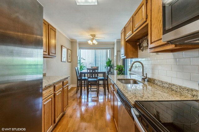 7033 N Kedzie Ave Unit 512, Chicago, IL 60645 - kitchen featuring appliances with stainless steel finishes, brown cabinets, tasteful backsplash, light wood finished floors, and light stone countertops