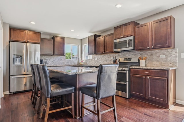 707 Brighton Dr, Pingree Grove, IL 60140 - kitchen with appliances with stainless steel finishes, a kitchen bar, dark wood-type flooring, tasteful backsplash, and recessed lighting
