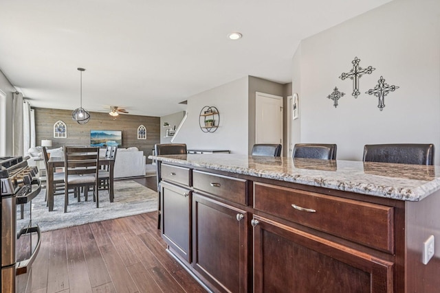 707 Brighton Dr, Pingree Grove, IL 60140 - kitchen featuring stainless steel gas range oven, a ceiling fan, wood walls, dark wood-style floors, and light stone countertops