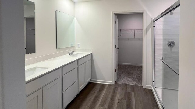 5025 Yates Dr, Mount Pleasant, WI 53403 - full bathroom with wood finished floors, double vanity, a spacious closet, and a shower with shower door