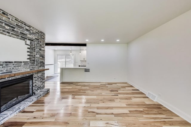 915 Carol Ave, Elgin, IL 60123 - unfurnished living room with light wood-style flooring, a brick fireplace, and recessed lighting