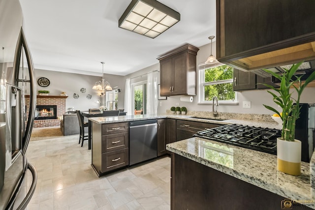 1878 Grassy Knoll Ct, Romeoville, IL 60446 - kitchen featuring appliances with stainless steel finishes, dark brown cabinetry, a brick fireplace, a peninsula, and a chandelier