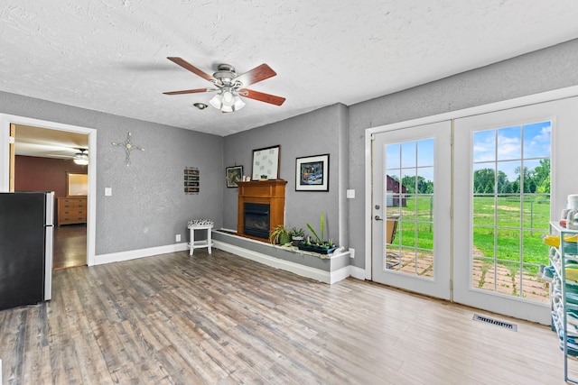6422 Steward Rd, Rockford, IL 61101 - unfurnished living room featuring a textured wall, a textured ceiling, ceiling fan, wood finished floors, and a glass covered fireplace