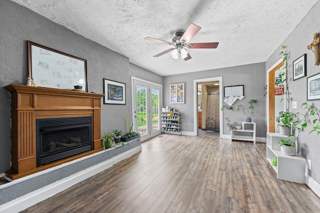 6422 Steward Rd, Rockford, IL 61101 - living room featuring wood finished floors, a textured wall, a fireplace with raised hearth, ceiling fan, and a textured ceiling