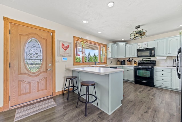 6422 Steward Rd, Rockford, IL 61101 - kitchen with black appliances, a peninsula, a breakfast bar, tasteful backsplash, and light countertops