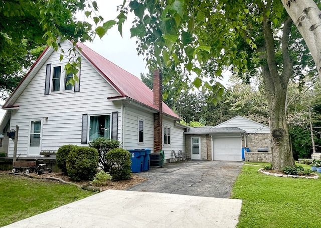 825 Swift Ave, Oglesby, IL 61348 - view of front of property featuring asphalt driveway, a metal roof, a front yard, a chimney, and an attached garage