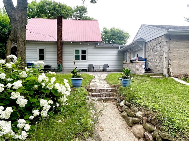 825 Swift Ave, Oglesby, IL 61348 - back of house featuring a chimney, a metal roof, and a lawn