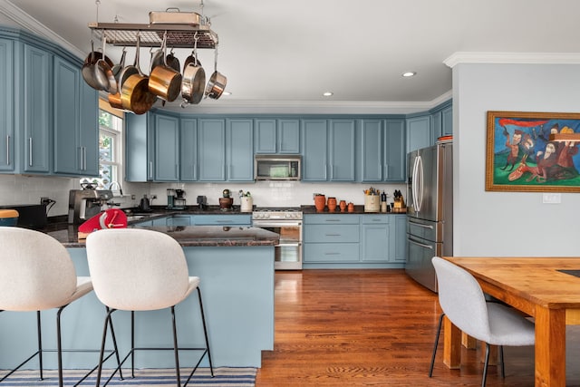 637 Highland Ave, Oak Park, IL 60304 - kitchen with appliances with stainless steel finishes, crown molding, blue cabinetry, a breakfast bar, and decorative backsplash