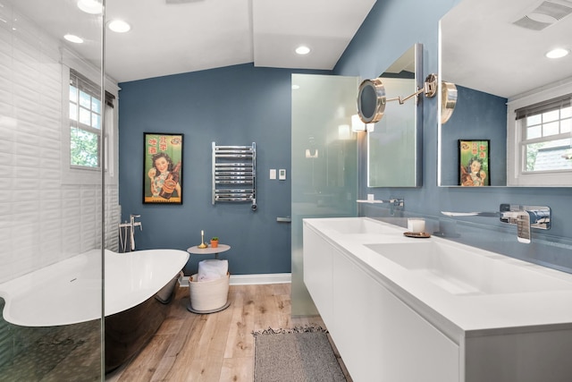 637 Highland Ave, Oak Park, IL 60304 - bathroom with radiator, wood finished floors, healthy amount of natural light, a freestanding tub, and lofted ceiling