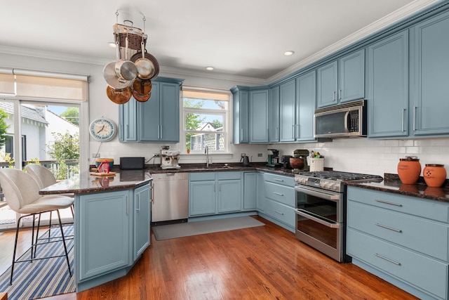 637 Highland Ave, Oak Park, IL 60304 - kitchen with appliances with stainless steel finishes, blue cabinets, a breakfast bar area, a peninsula, and crown molding