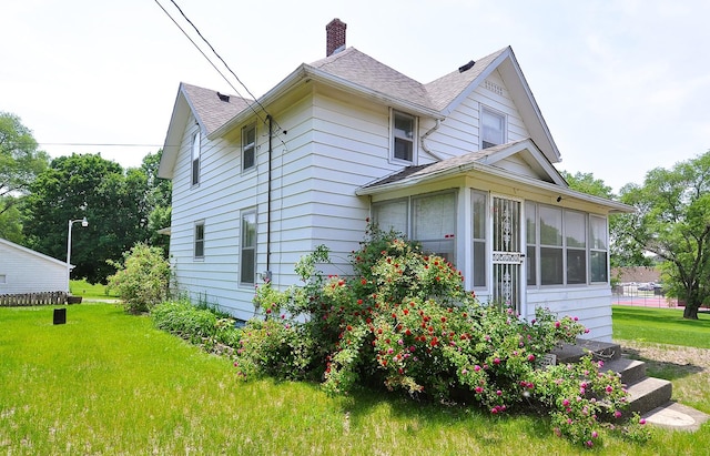 4816 Auburn St, Rockford, IL 61101 - view of home's exterior featuring a sunroom, a chimney, a yard, and a shingled roof