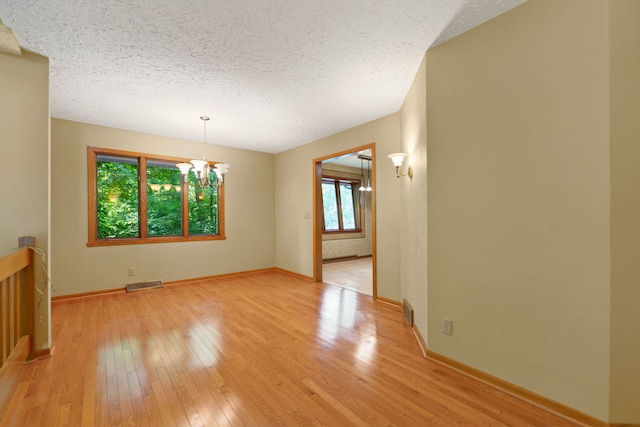 4303 Singleton Close, Rockford, IL 61114 - spare room with a chandelier, light wood-style flooring, and a textured ceiling
