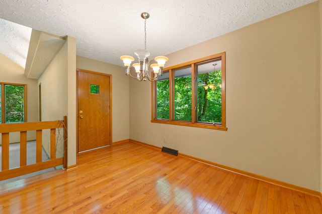 4303 Singleton Close, Rockford, IL 61114 - empty room featuring plenty of natural light, a chandelier, hardwood / wood-style flooring, and a textured ceiling