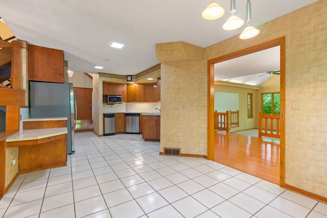 4303 Singleton Close, Rockford, IL 61114 - kitchen featuring appliances with stainless steel finishes, light countertops, light tile patterned flooring, brown cabinets, and vaulted ceiling