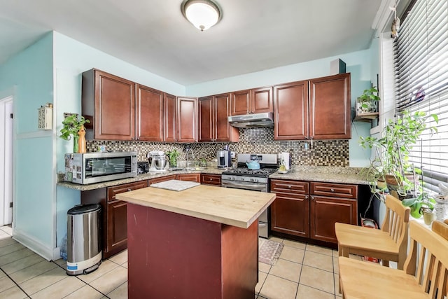 4444 N Spaulding Ave, Chicago, IL 60625 - kitchen with stainless steel appliances, under cabinet range hood, light tile patterned floors, and tasteful backsplash