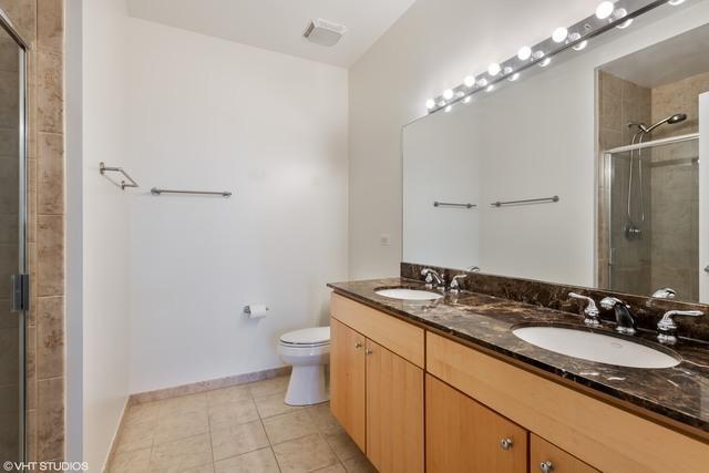 700 N Larrabee St Unit 1111, Chicago, IL 60654 - full bathroom with double vanity, a tile shower, and tile patterned flooring