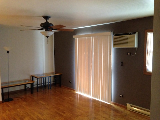 4305 W Shamrock Ln Unit 2F, Mchenry, IL 60050 - spare room featuring a baseboard radiator, an AC wall unit, ceiling fan, and wood finished floors