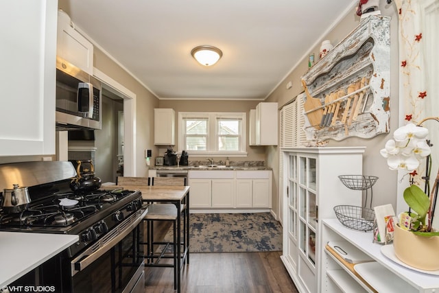 7718 Beach Rd, Wonder Lake, IL 60097 - kitchen featuring stainless steel appliances, dark wood-type flooring, light countertops, white cabinets, and ornamental molding