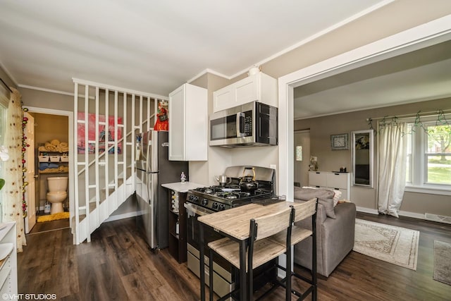 7718 Beach Rd, Wonder Lake, IL 60097 - kitchen featuring appliances with stainless steel finishes, dark wood-type flooring, white cabinets, crown molding, and light countertops
