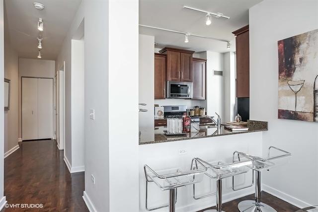 330 W Grand Ave Unit 2106, Chicago, IL 60654 - kitchen featuring stainless steel microwave, rail lighting, dark countertops, dark wood-style flooring, and a peninsula
