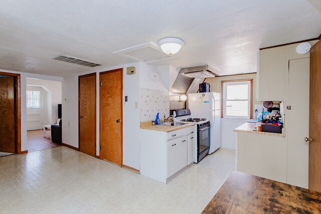 6444 N Oketo Ave, Chicago, IL 60631 - kitchen featuring range with gas cooktop, light floors, light countertops, freestanding refrigerator, and white cabinetry